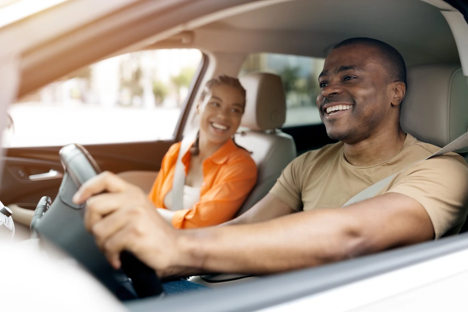 Concession automobile, remise de clés de véhicule entre vendeur et jeunes clients souriants